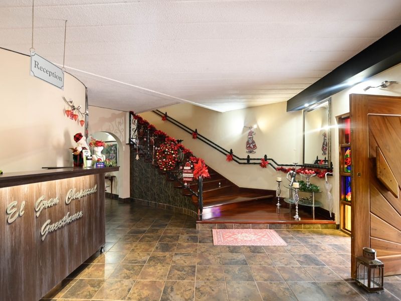 Welcoming entrance area featuring a reception desk, polished wooden staircase with wrought iron railings, and decorative tiled flooring.