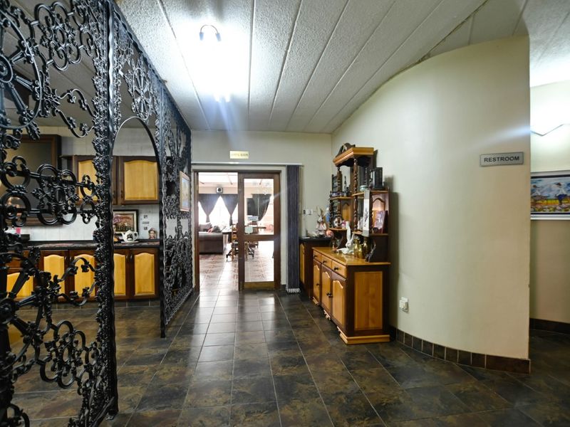 A spacious hallway featuring decorative wrought iron screening, tiled flooring, and a curved wall leading through a glass-panelled door into the living area.