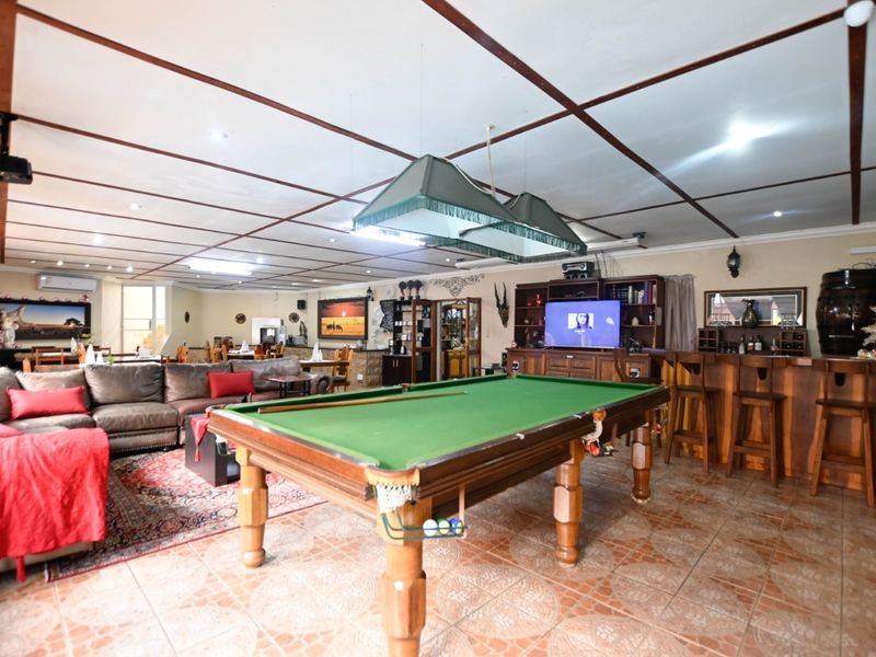 Spacious open-plan entertainment area featuring a built-in bar, tiled flooring, and a coffered ceiling, ideal for hosting and leisure activities.