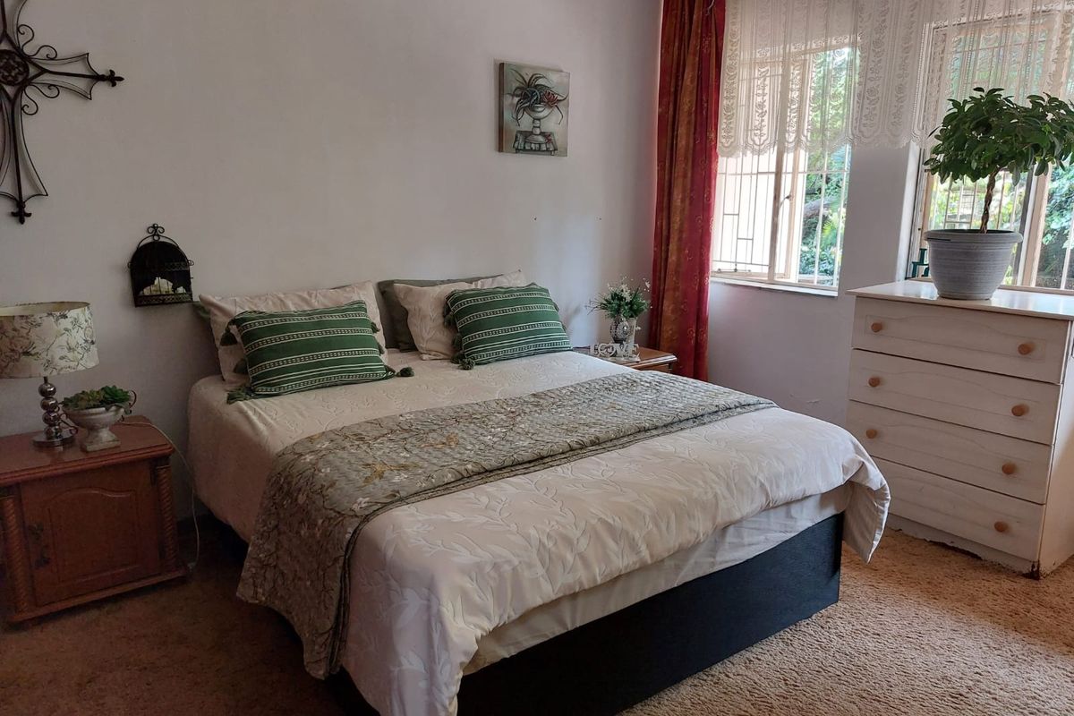 A cozy bedroom featuring carpeted flooring and a window fitted with security bars, offering a functional and comfortable living space.