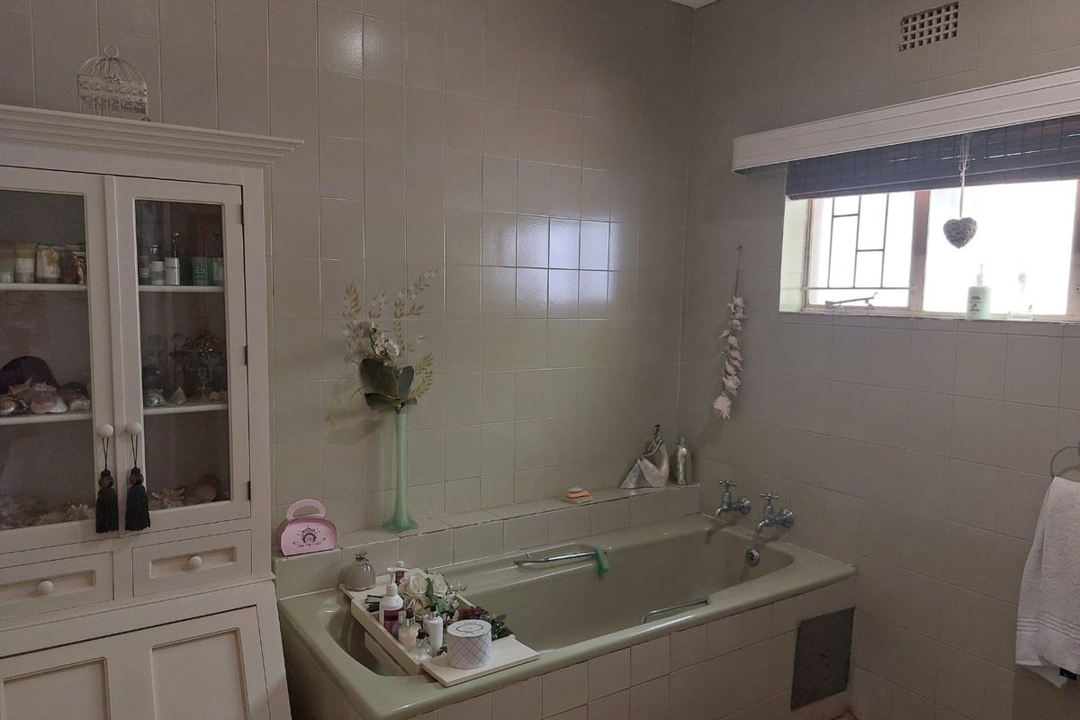 A functional bathroom featuring a built-in bathtub, tiled wall finishes, and integrated cabinetry, offering a classic layout with potential for modern updates.