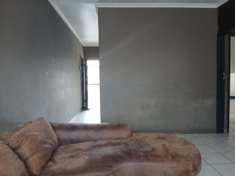 A living room area featuring tiled flooring and dark grey painted walls, leading towards an entrance or hallway.