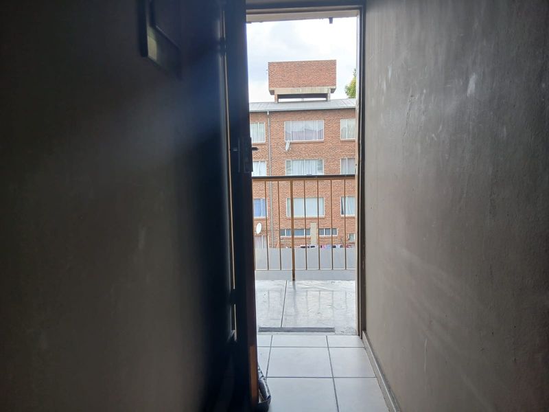 A view from an interior doorway looking out onto a small balcony with a metal balustrade and tiled flooring.