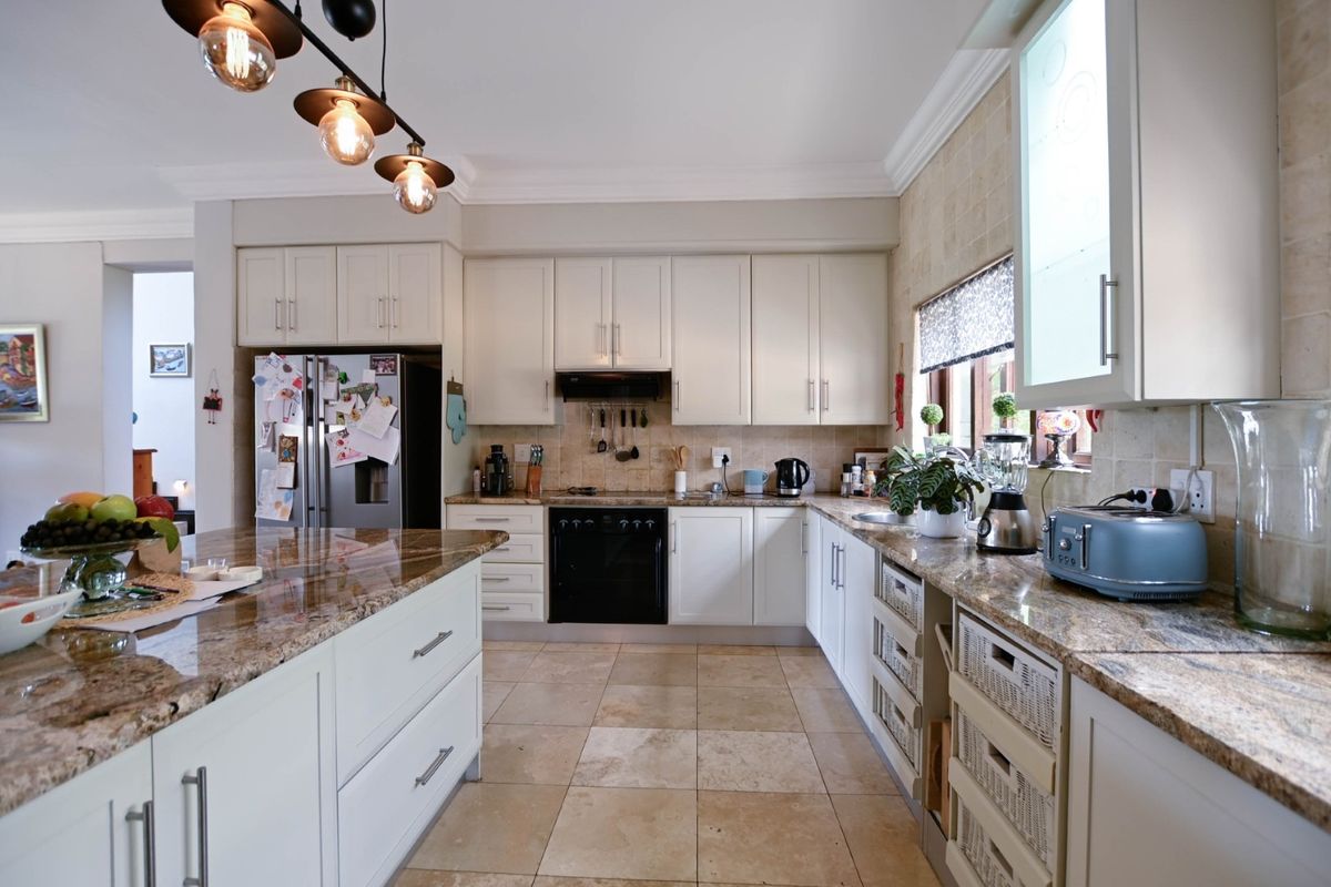 A well-appointed kitchen featuring granite countertops, a central island, built-in cabinetry, and tiled flooring, offering a functional and classic design.