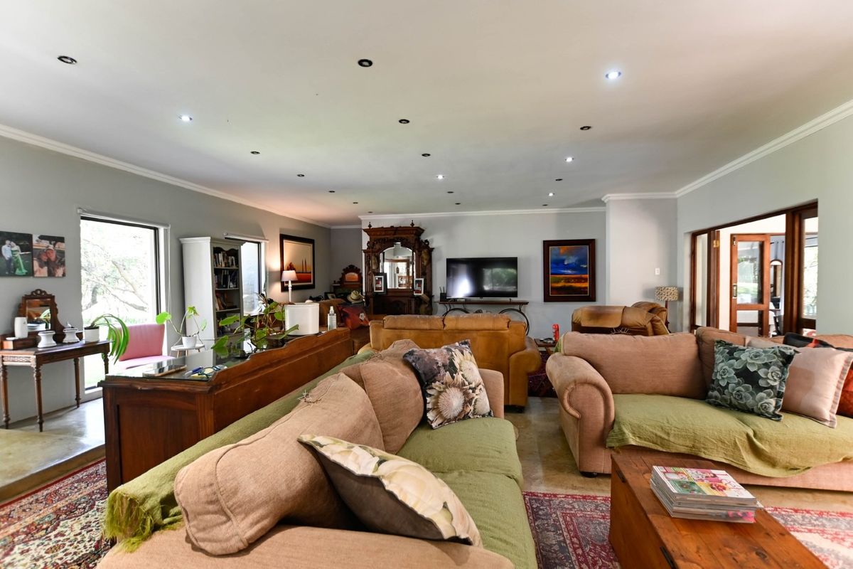 Spacious living room featuring recessed downlighting, coved cornicing, and tiled flooring, with large windows and sliding door access to the exterior.
