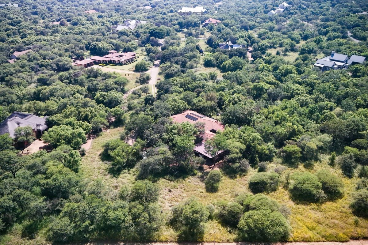 An aerial view of the property nestled within a lush, wooded estate, featuring a tiled roof with integrated solar panels.