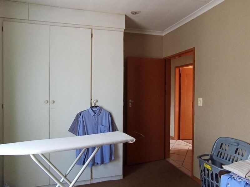 A bedroom featuring built-in cupboards and neutral wall finishes, providing a functional space with direct access to the hallway.