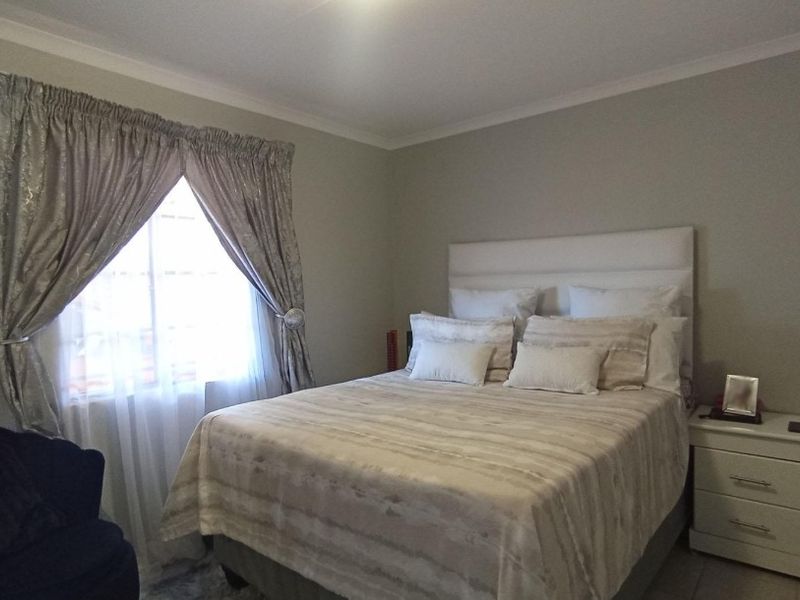 A well-maintained bedroom featuring neutral wall tones, tiled flooring, and decorative cove cornicing, providing a comfortable and functional sleeping space.