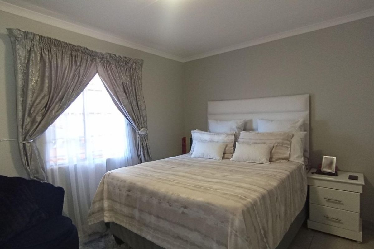 A well-maintained bedroom featuring neutral wall tones, tiled flooring, and decorative cove cornicing, providing a comfortable and functional sleeping space.