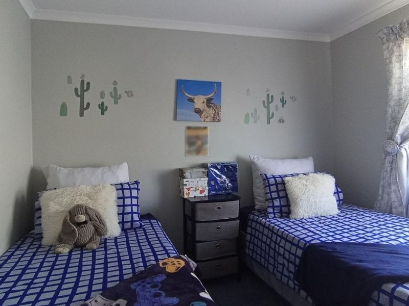 A functional bedroom featuring neutral wall finishes, cove cornicing, and a window with installed curtain rails.