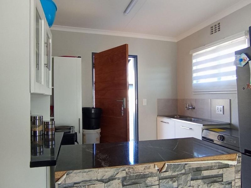Functional kitchen featuring built-in cabinetry, stone countertops, and a breakfast bar, with direct access to the exterior.