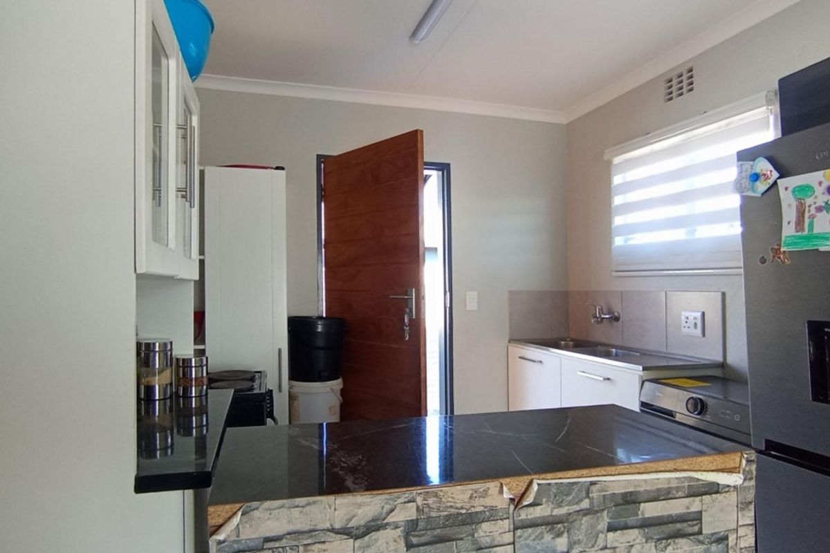 Functional kitchen featuring built-in cabinetry, stone countertops, and a breakfast bar, with direct access to the exterior.