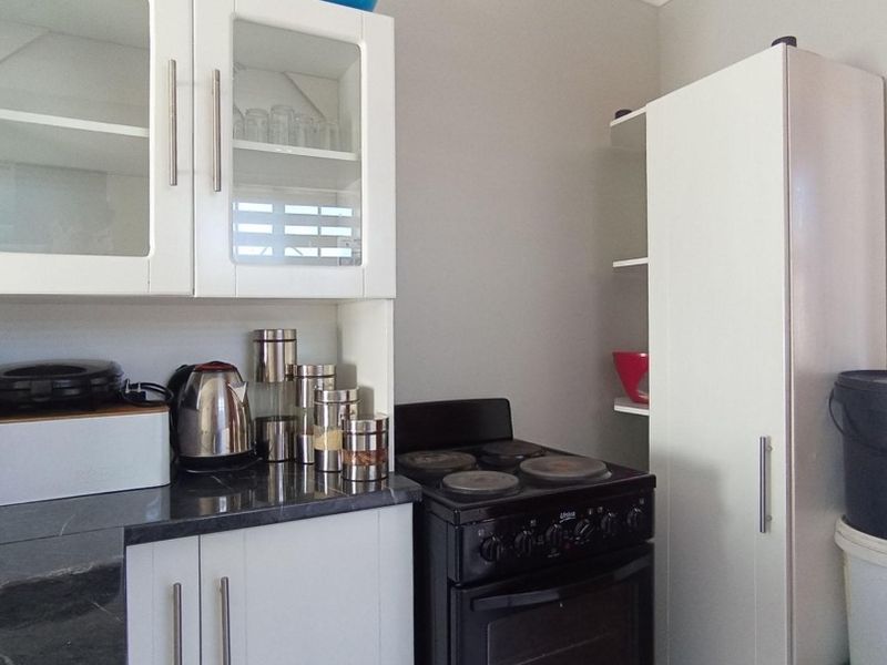 Compact kitchen area featuring white cabinetry, dark laminate countertops, and a freestanding electric stove with oven.