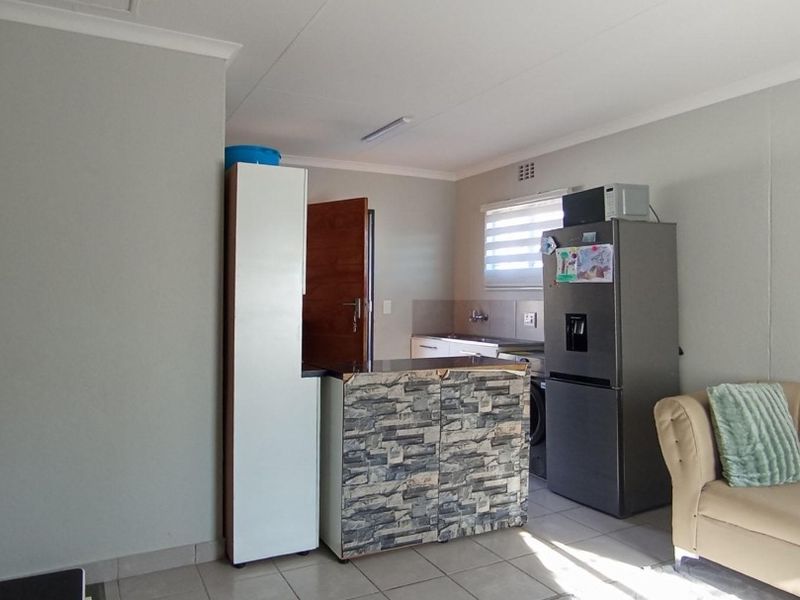 Open plan living area featuring tiled flooring and a compact kitchen space with built-in cabinetry and sink.