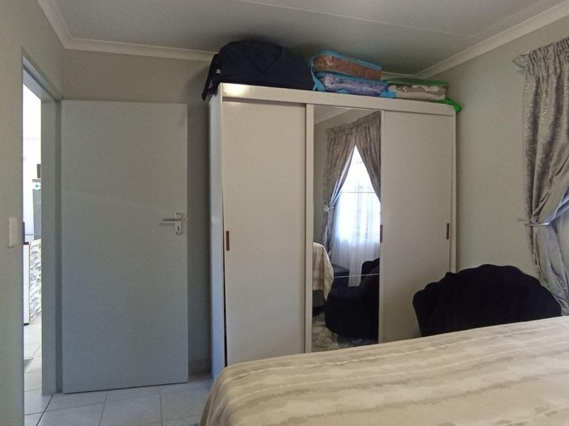 A bedroom featuring tiled flooring, cove cornicing, and a built-in wardrobe with mirrored panels.