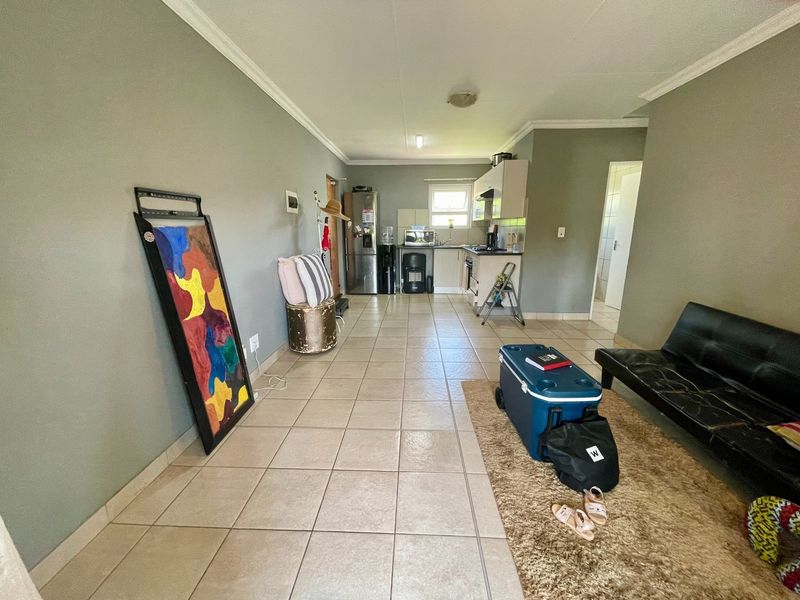 Open-plan living area featuring tiled flooring and a functional kitchen with built-in cabinetry, stove, and extractor fan.