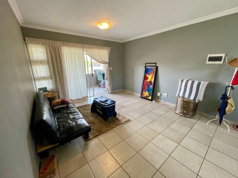 A living room featuring tiled flooring and a sliding glass door providing access to an outdoor area.