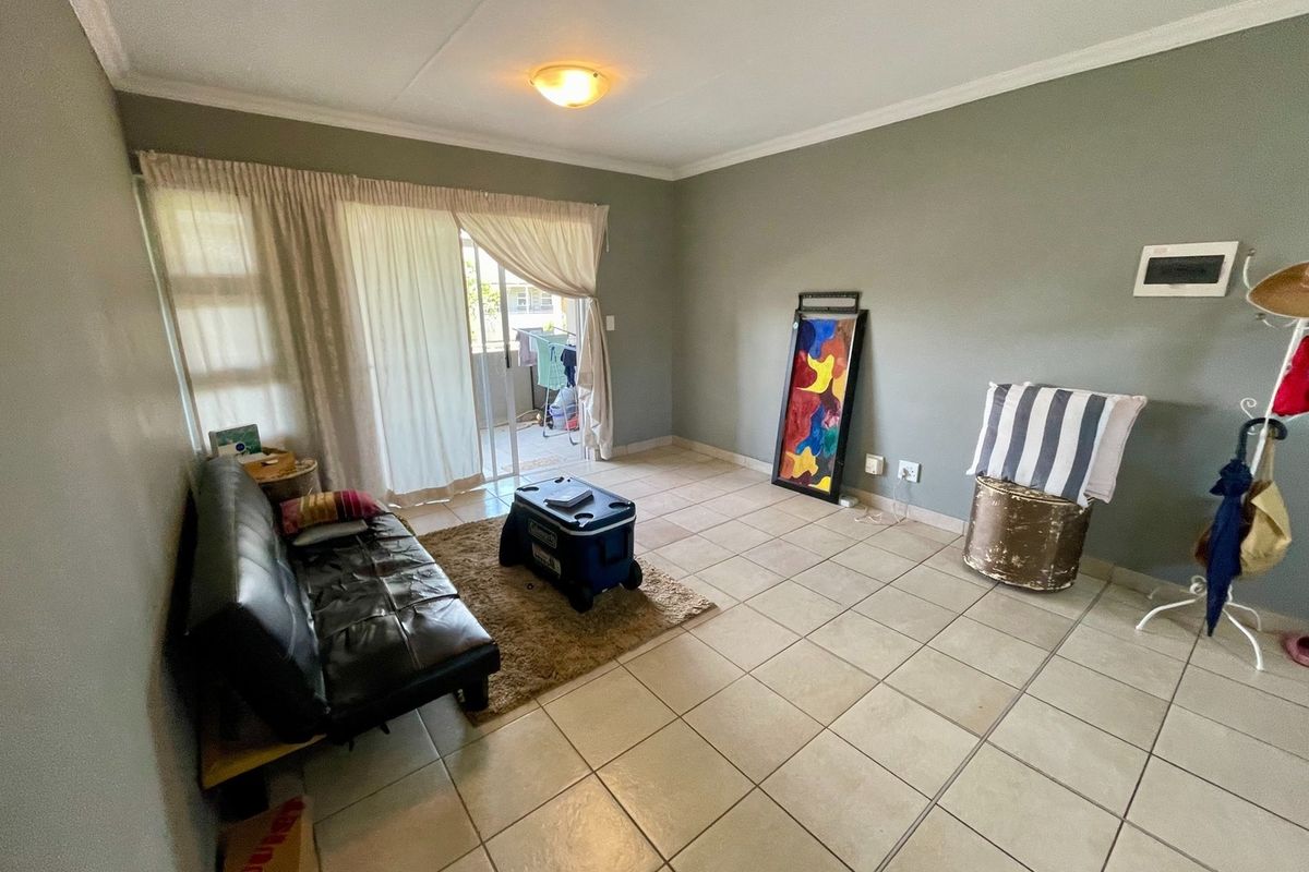 A living room featuring tiled flooring and a sliding glass door providing access to an outdoor area.