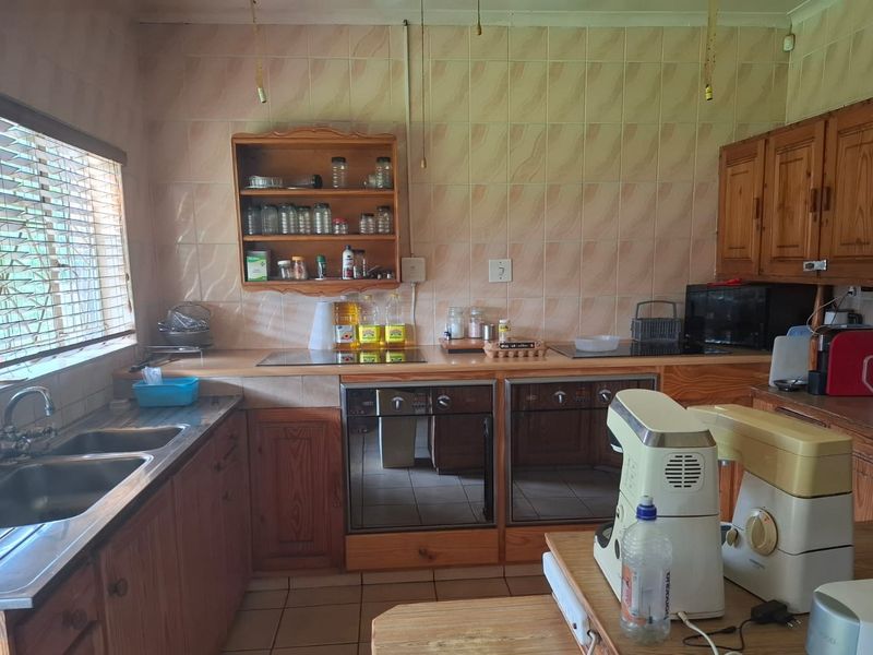 A functional kitchen featuring wooden cabinetry, a double oven, ceramic hob, and tiled splashback, offering a traditional layout with ample counter space.