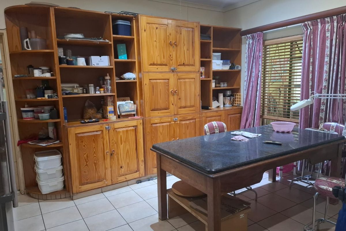 A kitchen area featuring extensive built-in wooden cabinetry and tiled flooring, offering ample storage space and a functional layout.