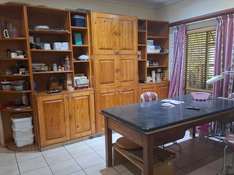A kitchen area featuring extensive built-in wooden cabinetry and tiled flooring, offering ample storage space and a functional layout.