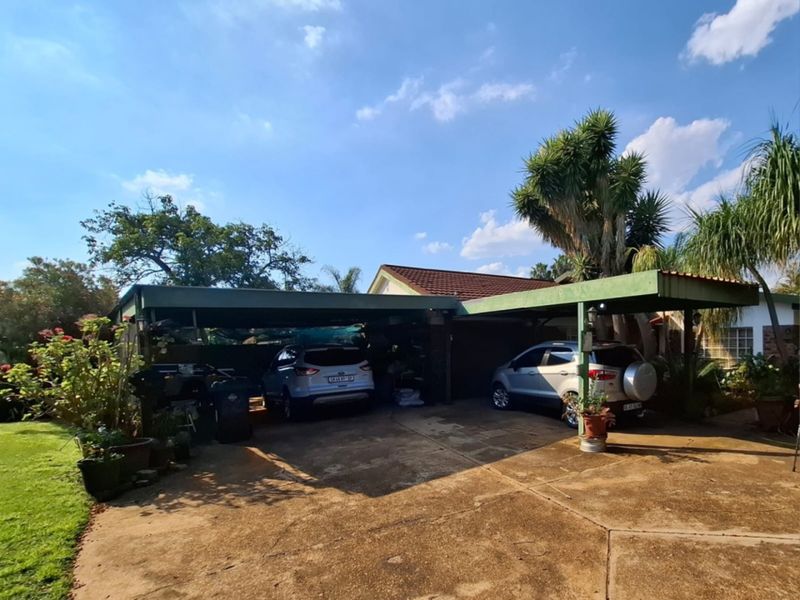 A spacious outdoor carport area providing covered parking, featuring a concrete driveway and direct access to the main property structure.