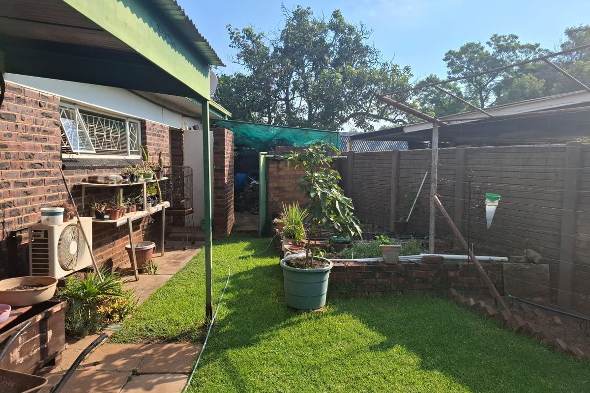 Rear garden area featuring a covered patio, brick boundary walls, and a metal pergola frame, offering potential for landscaping and outdoor living improvements.