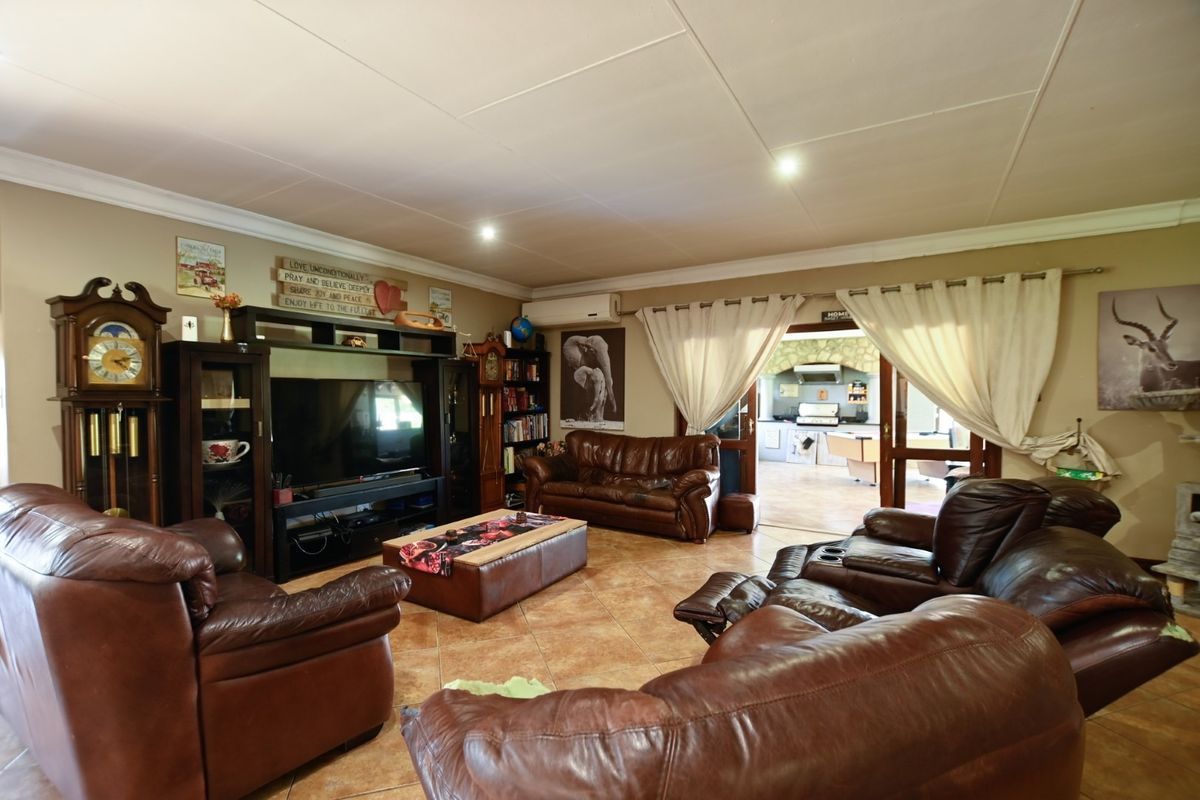 Spacious living room featuring tiled flooring, recessed lighting, and coved cornices, with double glass doors providing a view into the adjacent kitchen area.