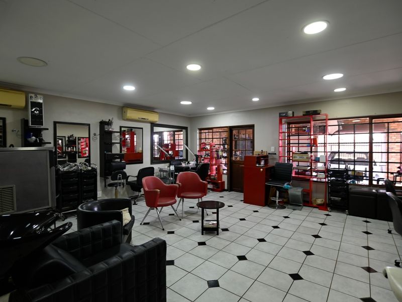 A commercial-style interior space featuring tiled flooring, recessed lighting, and wall-mounted air conditioning, currently configured as a salon.