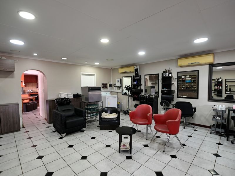 A spacious utility area currently utilized as a salon, featuring tiled flooring, recessed lighting, and wall-mounted air conditioning units.