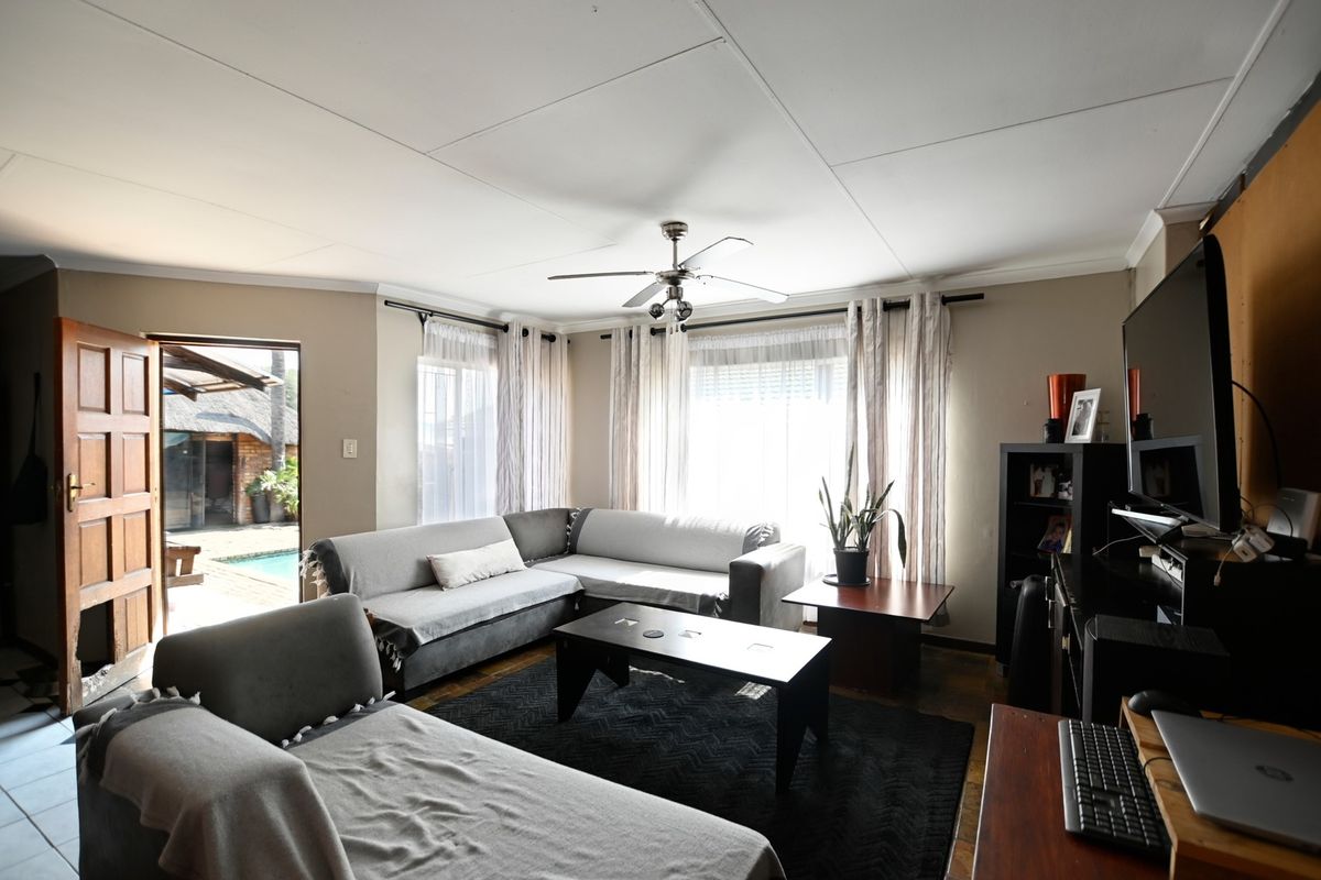 A comfortable living room featuring tiled flooring, a ceiling fan, and direct access to an outdoor patio and pool area.