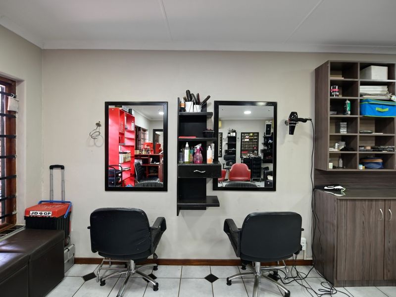 A functional utility space currently utilized as a salon, featuring built-in cabinetry, wall-mounted mirrors, and tiled flooring.