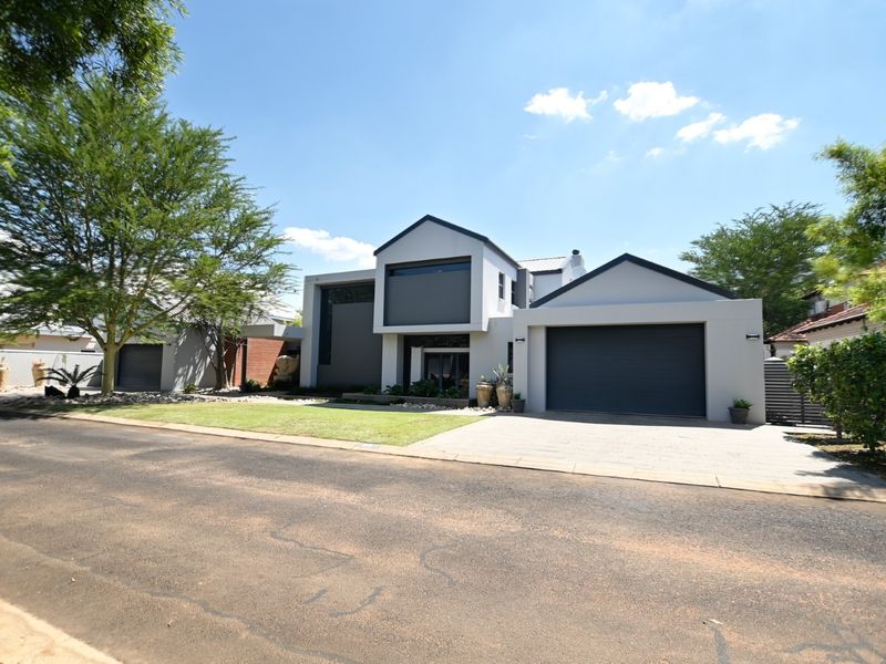 A modern, well-maintained residential property featuring a clean architectural facade, paved driveway, and double garage with manicured front lawn.