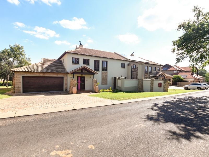 A well-maintained double-story residential property featuring a paved driveway, double garage, and attractive stone cladding accents on the front facade.