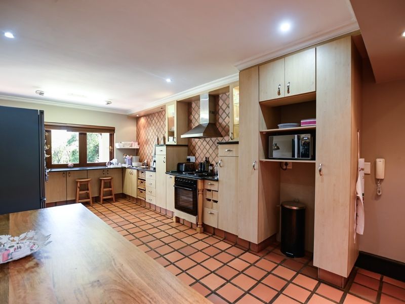 Spacious kitchen featuring light wood cabinetry, integrated appliances, tiled flooring, and ample counter space with a functional layout.