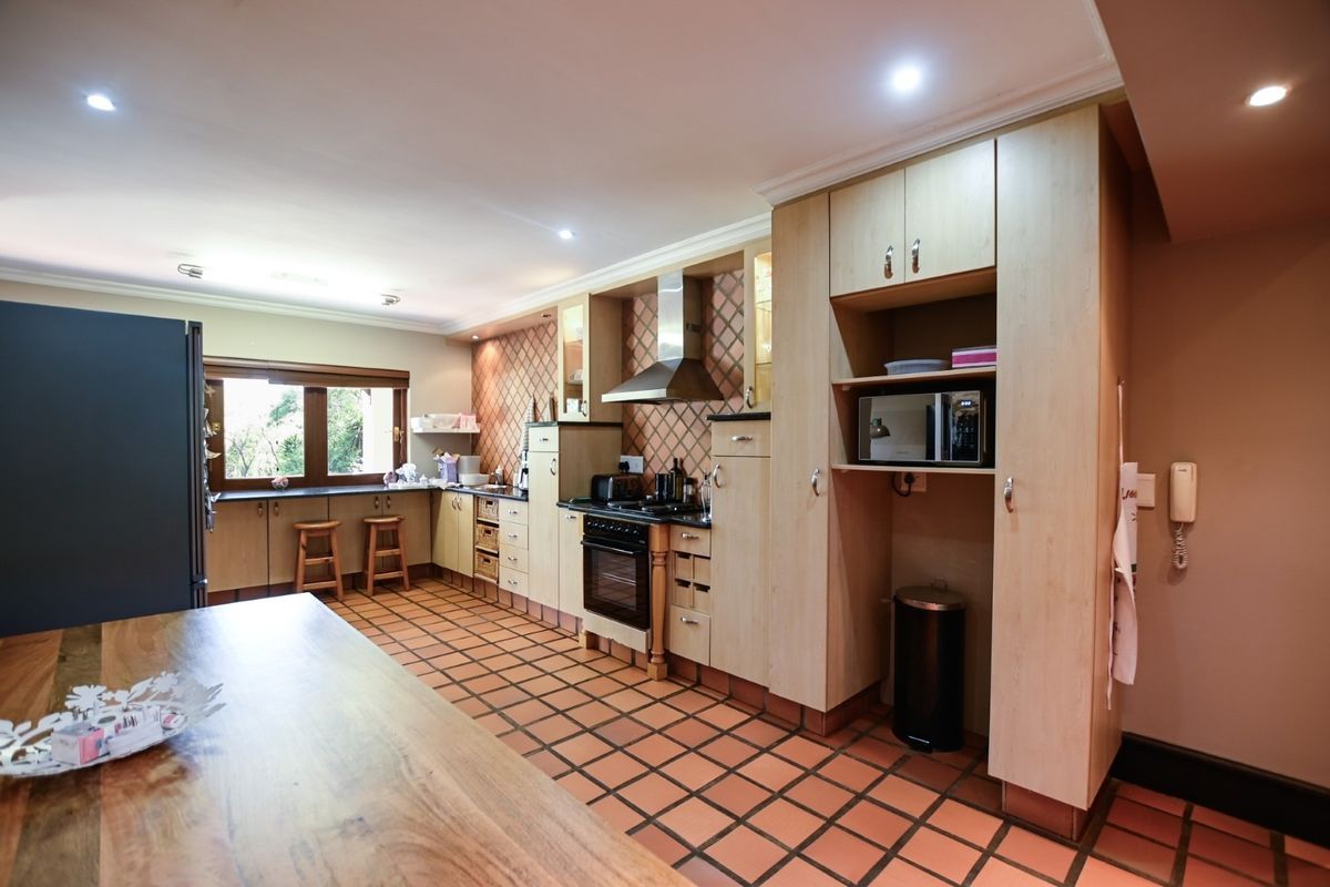 Spacious kitchen featuring light wood cabinetry, integrated appliances, tiled flooring, and ample counter space with a functional layout.