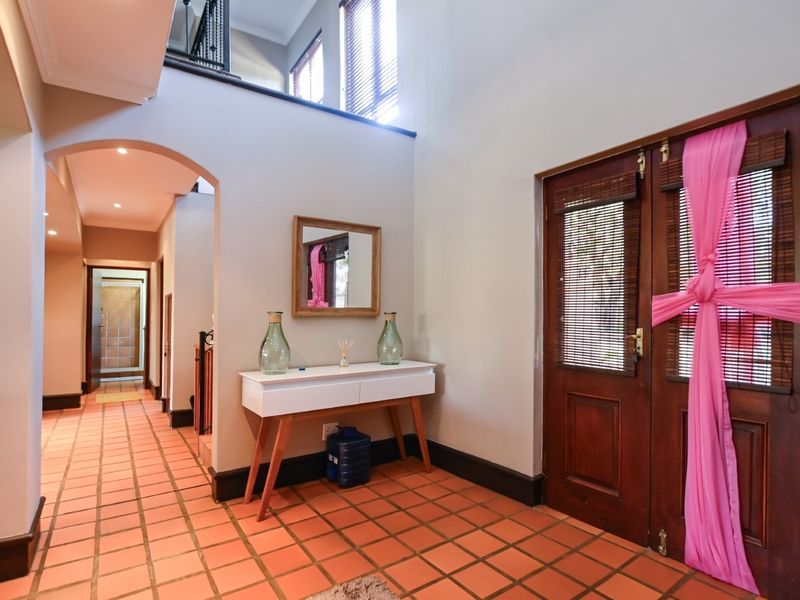 Spacious entrance hall featuring terracotta floor tiles, a welcoming archway, and double timber doors leading to the main living areas.