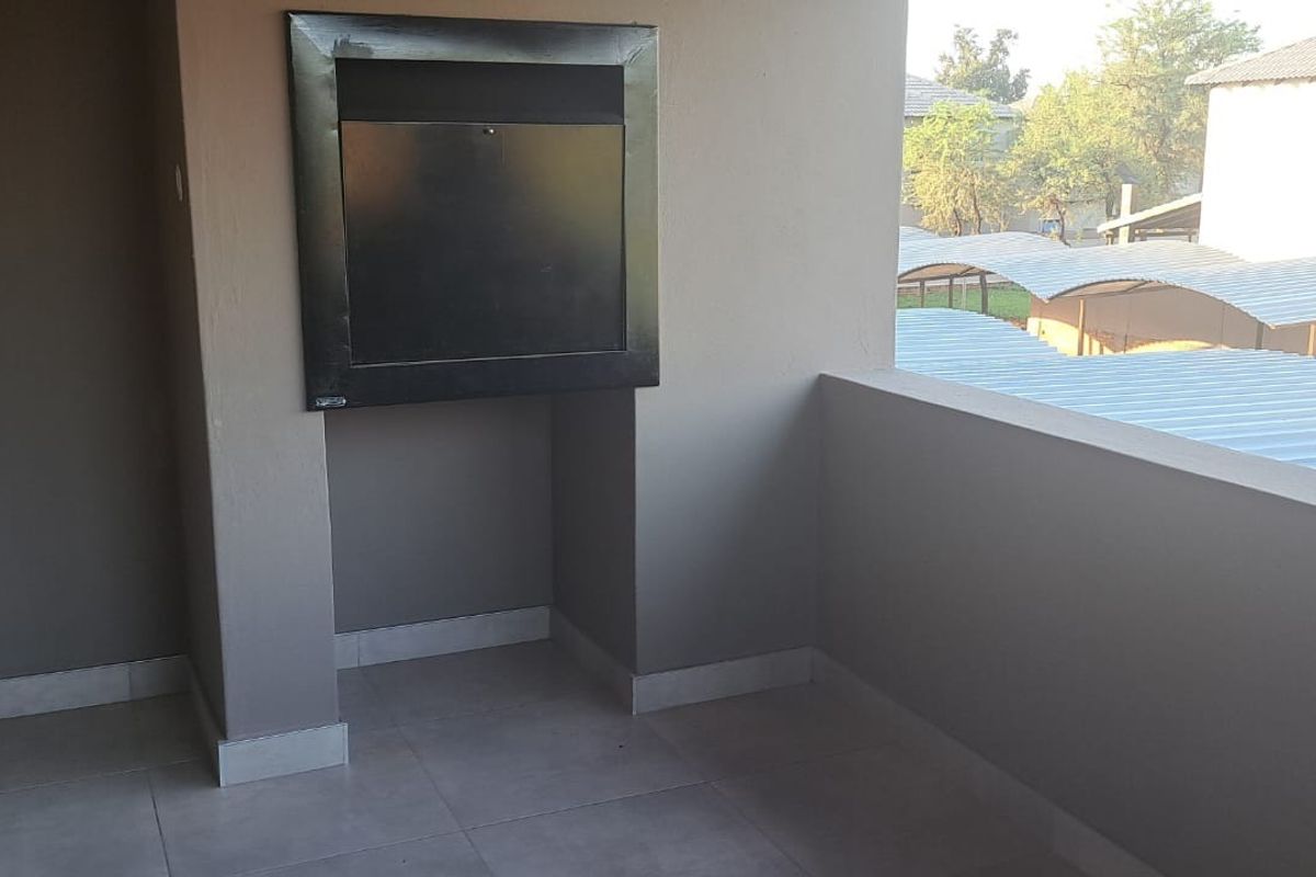 A covered balcony featuring a built-in braai and tiled flooring, offering an outdoor space suitable for entertaining.