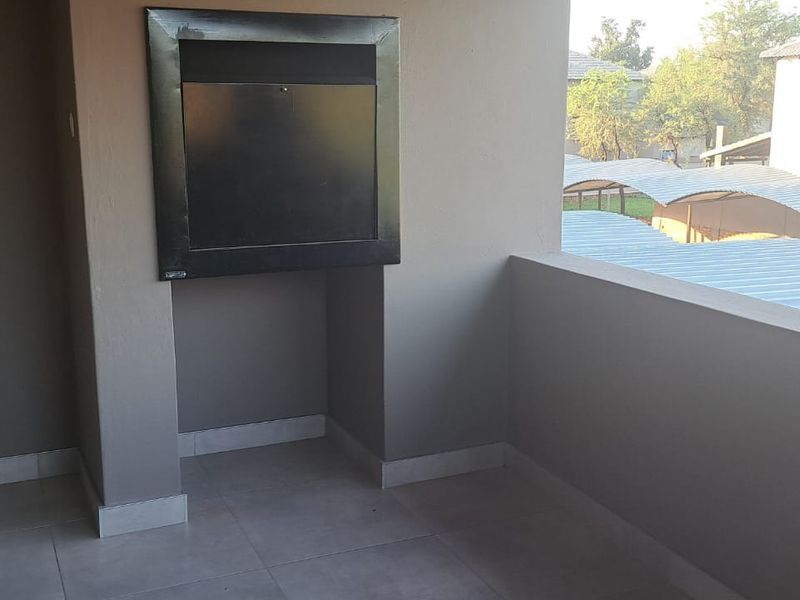 A covered balcony featuring a built-in braai and tiled flooring, offering an outdoor space suitable for entertaining.