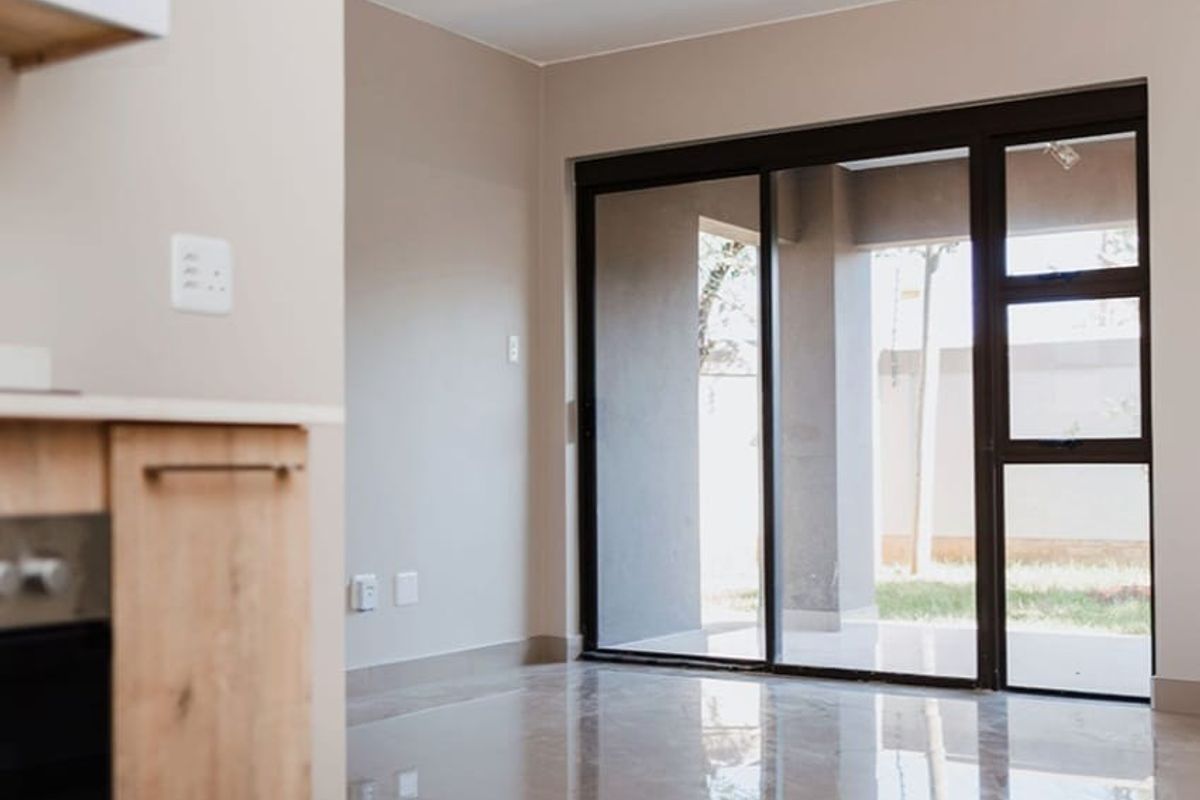 Modern open-plan living area featuring sleek tiled floors and large sliding glass doors that provide seamless access to the outdoor patio space.