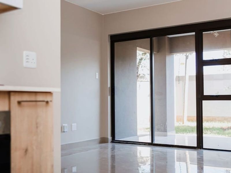Modern open-plan living area featuring sleek tiled floors and large sliding glass doors that provide seamless access to the outdoor patio space.