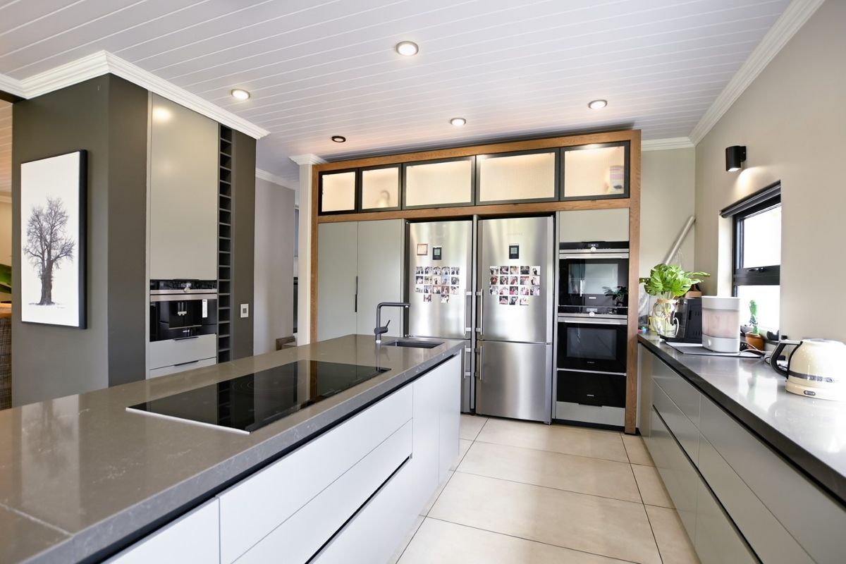 Modern kitchen featuring a large island with induction cooktop, stone countertops, integrated appliances, and ample cabinetry with a clean, contemporary finish.