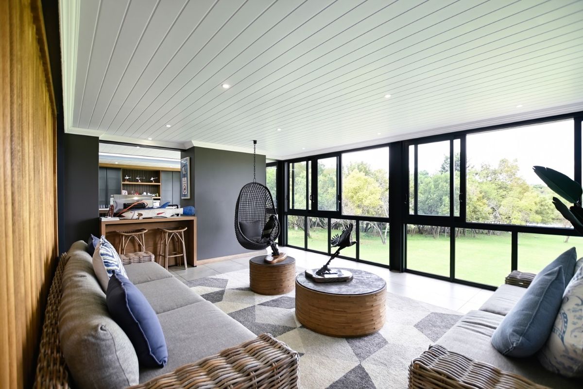 Spacious living area featuring a tongue and groove ceiling, recessed lighting, and large black aluminium sliding doors offering views of the garden.