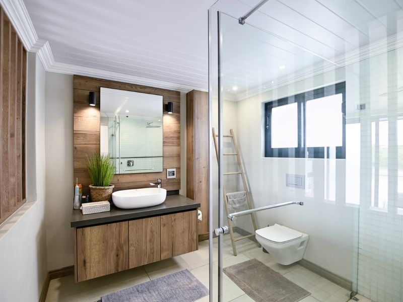 Modern bathroom featuring a floating timber vanity, vessel sink, wall-mounted toilet, and a spacious glass-enclosed shower with contemporary finishes.