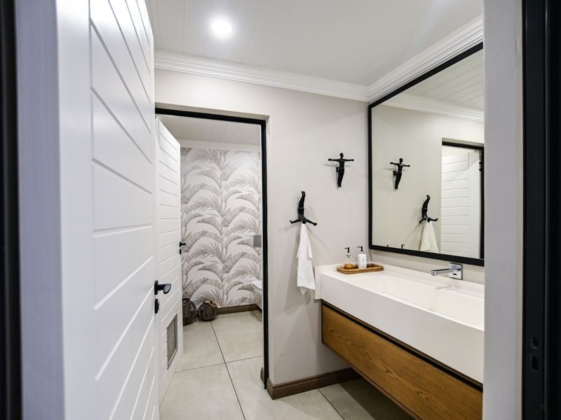 Modern bathroom featuring a floating vanity with integrated basin, large framed mirror, and stylish tiled flooring with a separate toilet area.