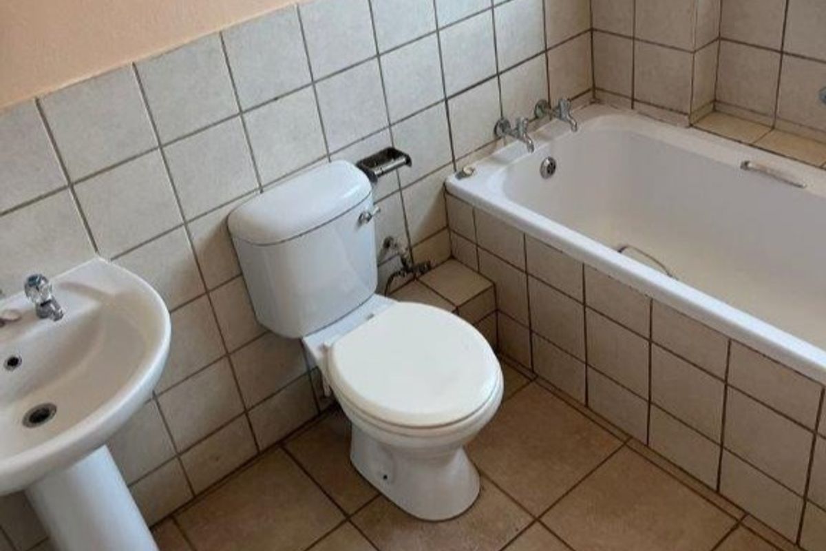 A dated bathroom featuring a pedestal basin, standard toilet, and bathtub with ceramic wall and floor tiling.