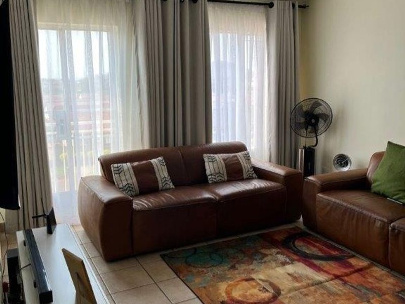 A comfortable living room featuring tiled flooring and a large sliding glass door that provides access to the balcony area.