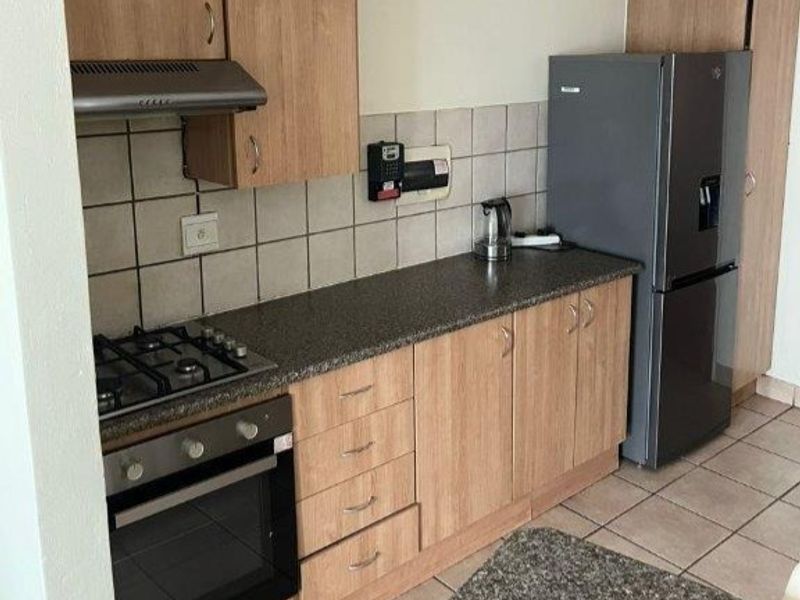 A functional kitchen featuring light wood cabinetry, granite-look laminate countertops, a gas hob, built-in oven, and tiled flooring.