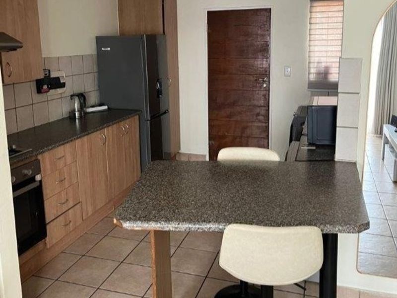 A functional kitchen featuring laminate cabinetry, granite-look countertops, a built-in oven, and a breakfast bar, finished with tiled flooring and backsplash.