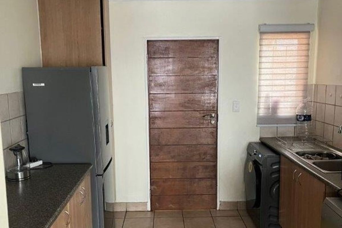A functional kitchen featuring laminate cabinetry, tiled flooring, and a tiled backsplash, offering a practical layout with potential for modern cosmetic updates.